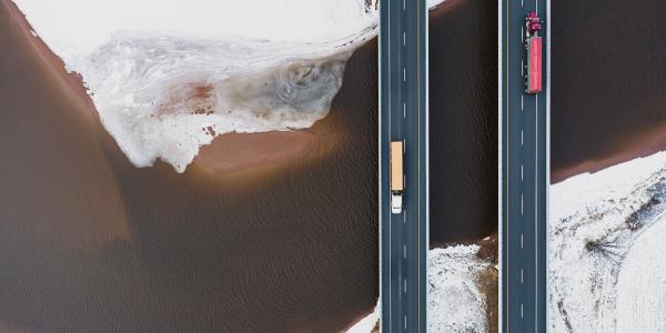 Two trucks on roads driving over ocean and brown land