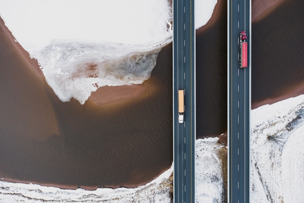 Two trucks on roads driving over ocean and brown land